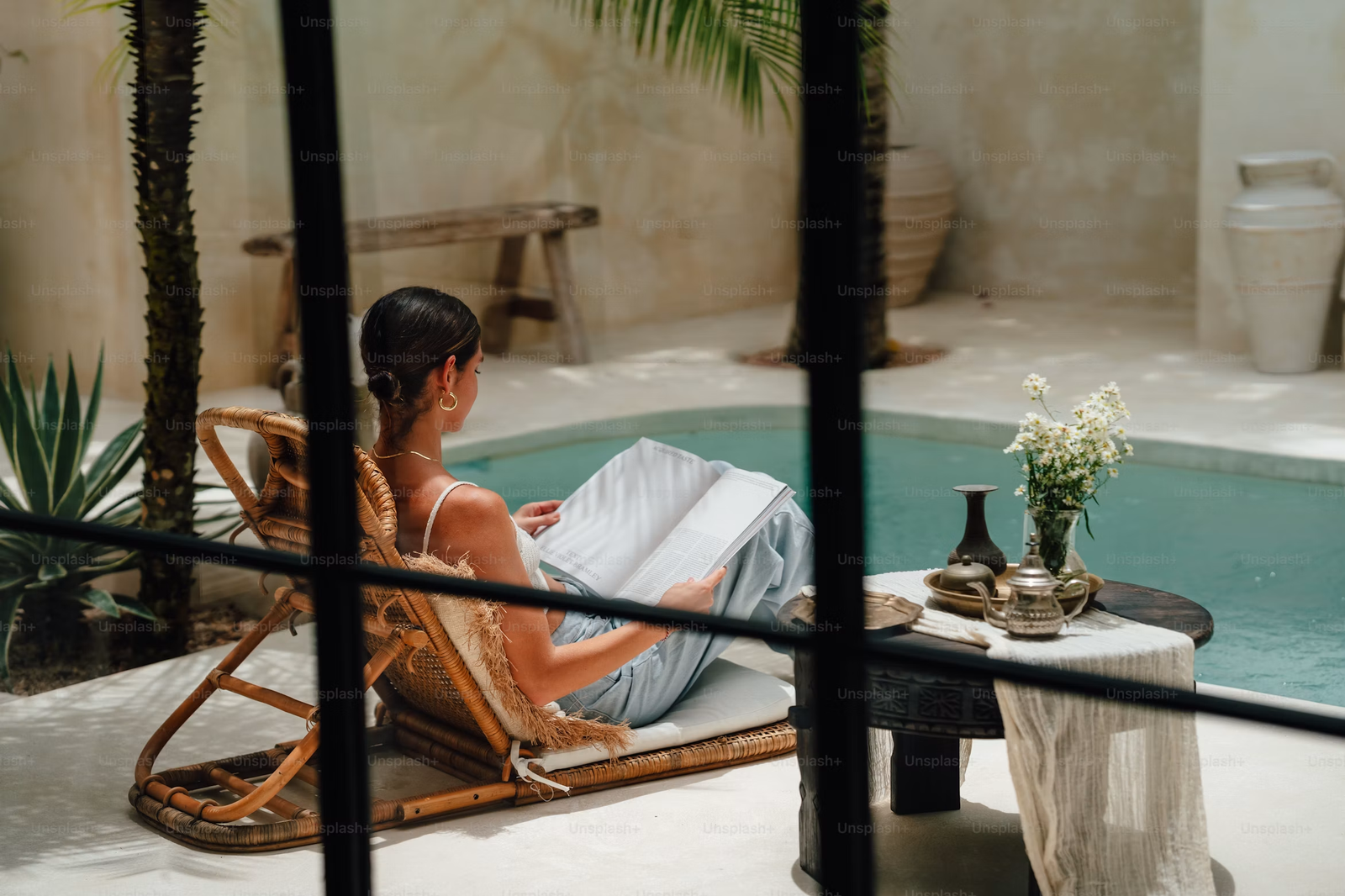 A guest relaxing beside a sunlit courtyard pool